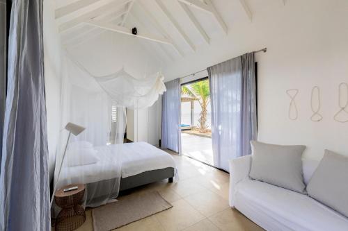 a white bedroom with a bed and a couch at Oceanfront 72 & Sunny in Kralendijk