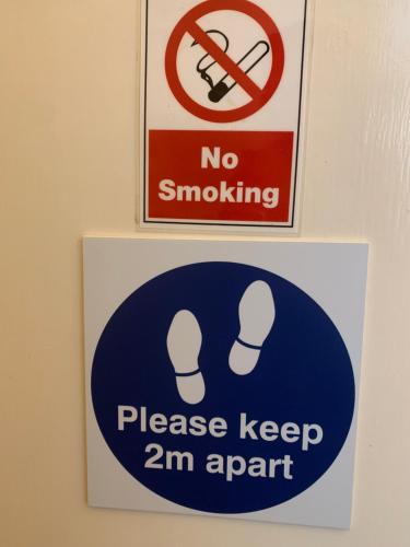 dois sinais na parede com um sinal que diz para não fumar e, por favor, manter em Manor Lodge Guesthouse em Keynsham