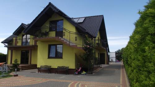 a yellow house with a balcony on a street at Pokoje typu Studio OLSZYNA in Ustronie Morskie