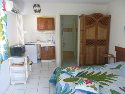 a bedroom with a bed and a small kitchen at Résidence des îles in Le Marin
