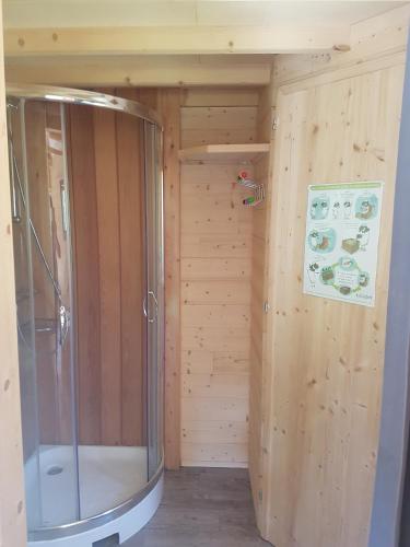 La salle de bains est pourvue d'une douche et d'un mur en bois. dans l'établissement Insolite Tiny House Sérénité Bien Être, à Ban-sur-Meurthe-Clefcy