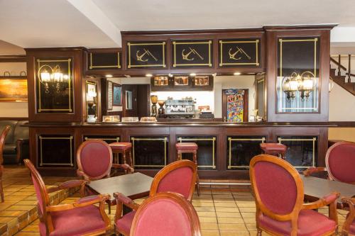 un restaurante con un bar con mesas y sillas rojas en Hotel Las Anclas en El Astillero