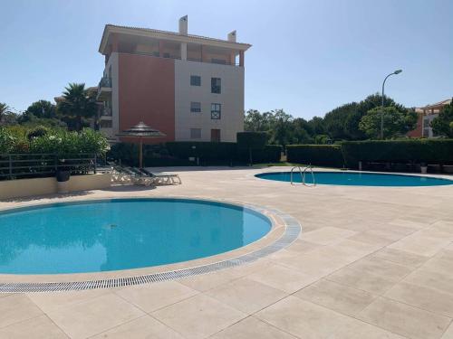 duas piscinas em frente a um edifício em Corcovada Lote 35 em Albufeira