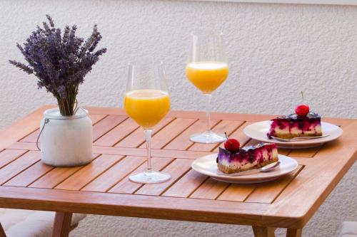 a wooden table with two glasses of orange juice and desserts at Apartmani Rustica in Drasnice
