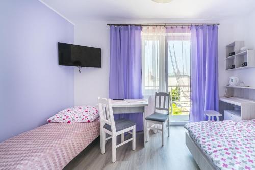 a bedroom with two beds and a desk and a window at Pokoje Iga in Władysławowo