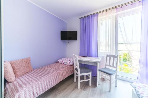 a small room with a bed and a desk and a window at Pokoje Iga in Władysławowo