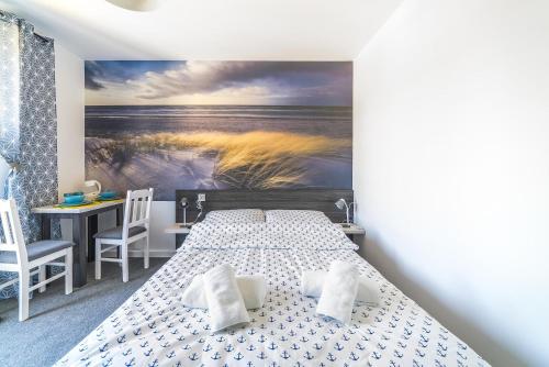 a bedroom with a bed and a painting of a beach at Pokoje Iga in Władysławowo