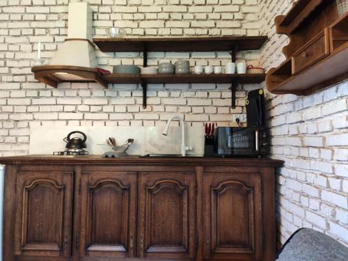 a kitchen with a wooden cabinet against a brick wall at Srokowski Dwór 1 - Stara Kuźnia - Prywatna Sauna ! in Srokowo