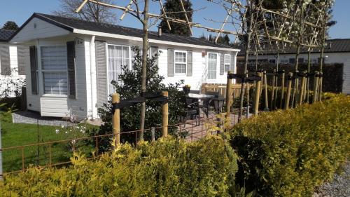 a white house with a fence in front of it at Bospareltjes Luxe chalets Alleen voor recreatie in Oisterwijk