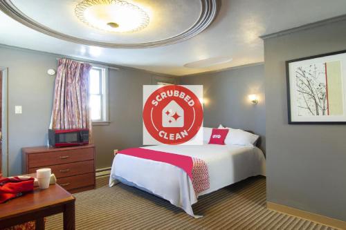 a hotel room with a bed and a sign on the wall at OYO Hotel Wilkes-Barre East in Wilkes-Barre