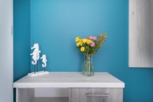 a table with a vase of flowers on a blue wall at Pokoje Iga in Władysławowo