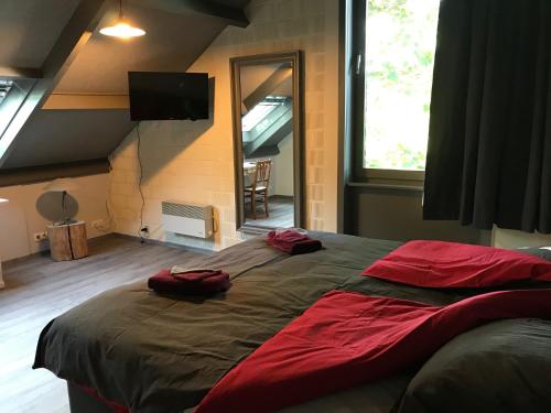 a bedroom with a large bed with red pillows on it at Grysperre B&B in Hooglede