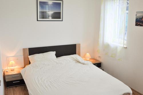a bedroom with a white bed with two lamps on tables at Apartment Lavandula in Labin