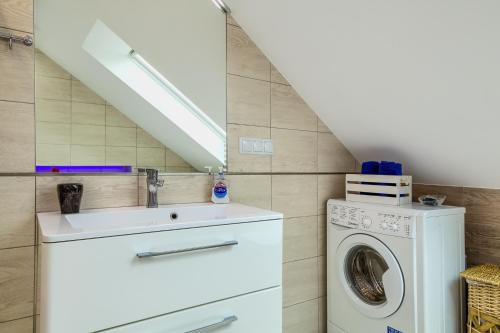 a bathroom with a sink and a washing machine at Apartament Rynek in Tylicz