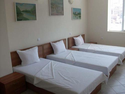two beds in a room with white sheets and pillows at Versai Hotel in Svishtov