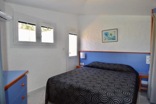 a small bedroom with a bed and two windows at Le Domaine de VILLEPEY By SdR in Fréjus
