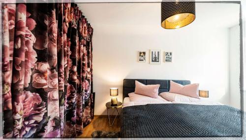 a bedroom with a bed with pink pillows and a curtain at Ferienwohnung Seeblick Grundlsee - Your Austrian Home in Grundlsee