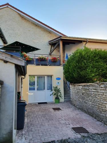 una casa con una puerta blanca y una pared de piedra en L'Oustalou en Viéville