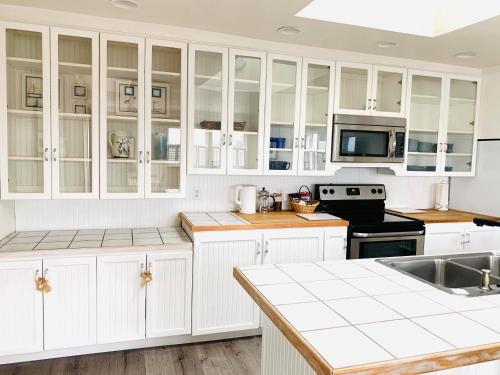 a kitchen with white cabinets and white appliances at Boardwalk Cottages in Long Beach