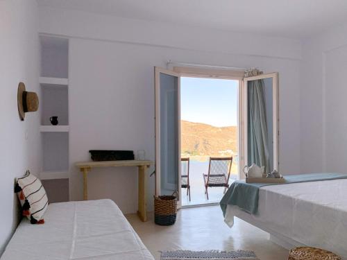 Habitación blanca con cama y ventana grande. en Almyriki en Mylopotas