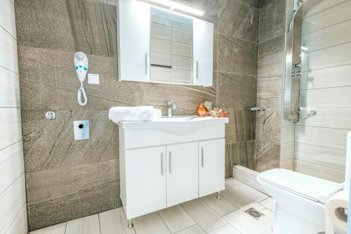 a bathroom with a white sink and a shower at Design Suites Efharis (Sauvignon) in Nea Peramos