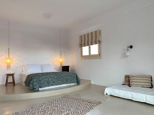 a white bedroom with two beds and a rug at Almyriki in Mylopotas