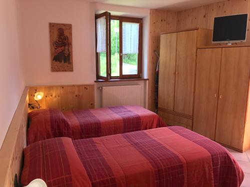 a bedroom with two beds and a tv on the wall at Appartamento Andalo per famiglie, lontano dal caos in Andalo