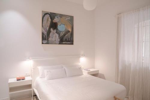 a bedroom with a white bed and a painting on the wall at NUEVO Katu Kale Apartamentuak CENTRO HISTORICO in Getaria