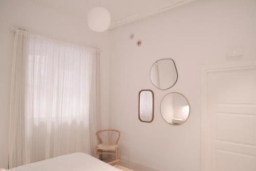 a white bedroom with two mirrors and a chair at NUEVO Katu Kale Apartamentuak CENTRO HISTORICO in Getaria
