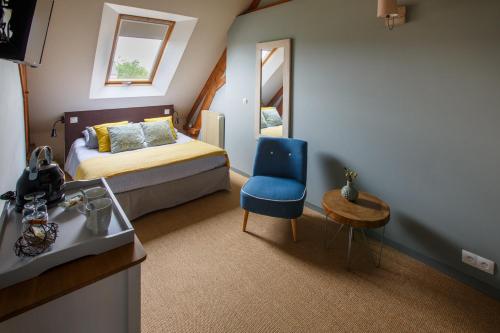 um pequeno quarto com uma cama e uma cadeira azul em LE CLOS POULAIN Petits gîtes de charme et chambres d'hôtes Familiales au calme proche Bayeux et des plages em Nonant