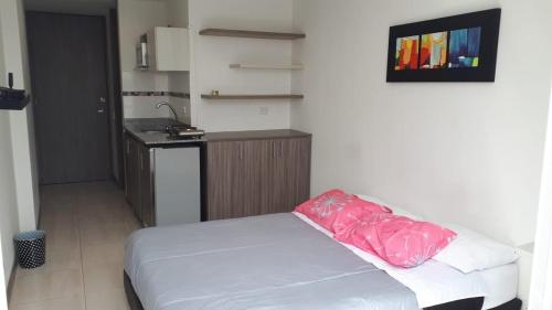 1 dormitorio con cama blanca y almohada rosa en Apartaestudio Pereira, en Pereira