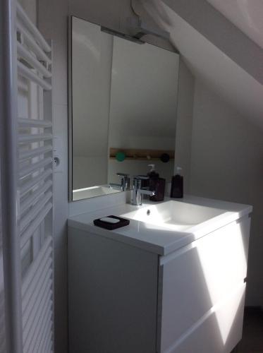 een witte badkamer met een wastafel en een spiegel bij Villa Liluda in Barneville-Carteret