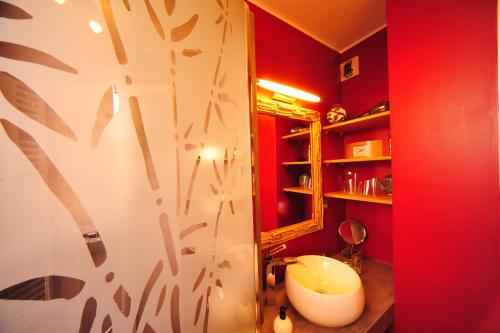 een rode badkamer met een wastafel en een spiegel bij Magic Moments Appartement in Annecy