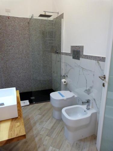 a bathroom with a toilet and a sink and a shower at Clelia's Boutique Rooms & Suites in La Maddalena