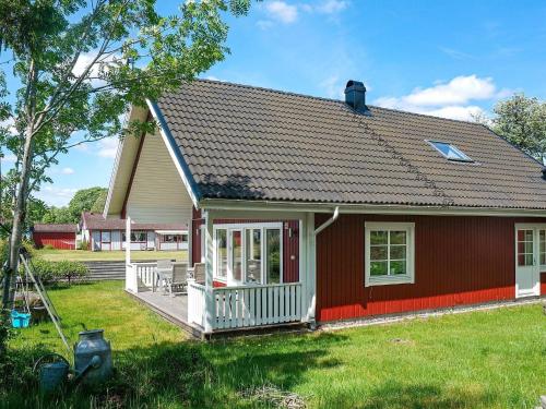 ein kleines rotes Haus mit einer Veranda und einem Hof in der Unterkunft 6 person holiday home in Unnaryd in Unnaryd
