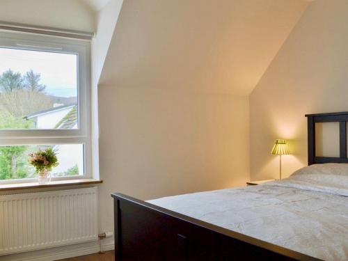 a bedroom with a bed and a large window at The Coolins cottage with wood burner in Strathcarron