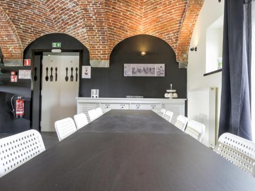 una sala de conferencias con mesa negra y sillas blancas en Large house ideal for families, en Houyet