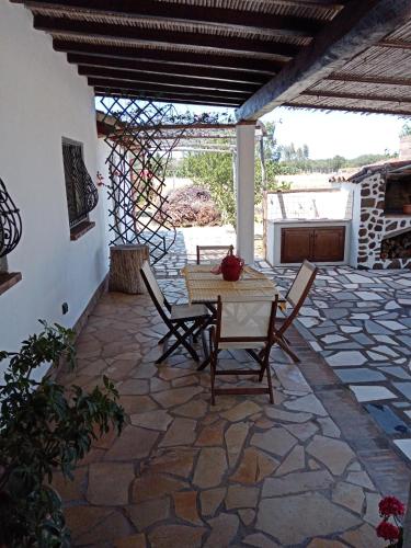 a patio with a table and chairs on a stone floor at VILLA LUPINO in Orosei