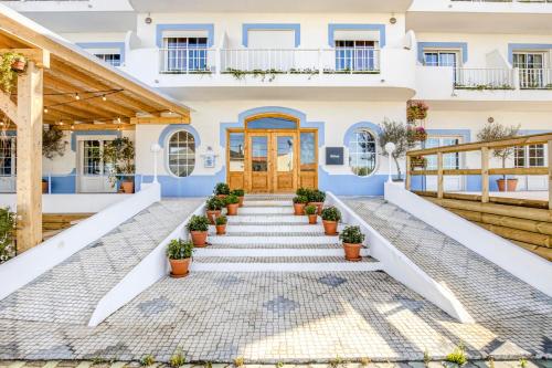 een huis met blauwe muren en trappen met potplanten bij Selina Peniche in Peniche