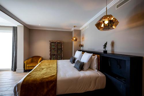 a bedroom with a large bed and a chandelier at Hôtel L'Incomparable Aix-Les-Bains in Tresserves