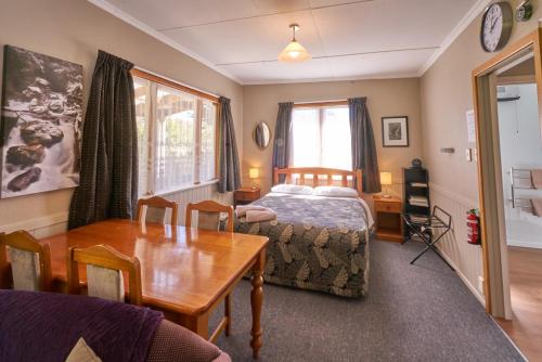 a bedroom with a bed and a table and a dining room at Accommodation Fiordland The Bach - One Bedroom Cottage at 226B Milford Road in Te Anau