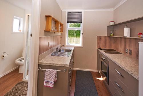 a small kitchen with a sink and a toilet at Accommodation Fiordland The Bach - One Bedroom Cottage at 226B Milford Road in Te Anau