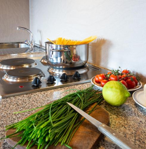 a kitchen counter with tomatoes and a pot on a stove at B & B Apartments Ortlerblick in Sluderno