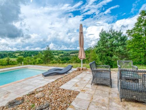 a patio with an umbrella and chairs next to a swimming pool at Quaint Villa in Aquitaine with Swimming Pool in Saint-Alvère