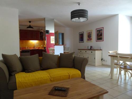 a living room with a yellow couch and a kitchen at Les Manades in Aigues-Mortes