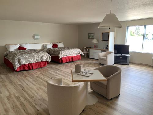 Cette chambre d'hôtel comprend deux lits, une table et des chaises. dans l'établissement Motel Chute des Pères, à Dolbeau-Mistassini