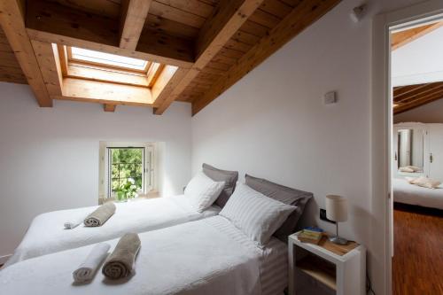 two beds in a bedroom with white walls and wooden ceilings at BELLA VITA! in Bellagio