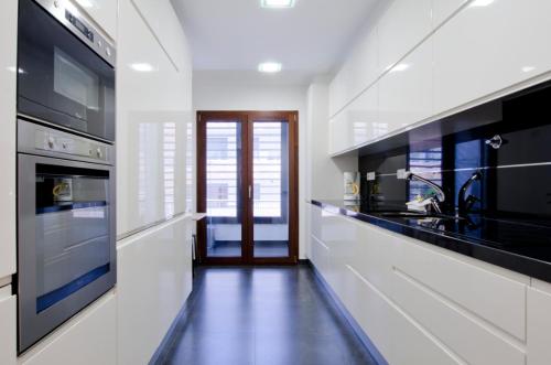 a kitchen with black and white appliances and a hallway at Parque Nações / Jardins Cristo Rei in Lisbon