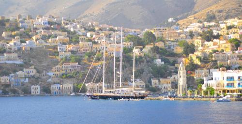 a sail boat in the water in front of a city at Odyssia in Symi