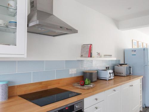 a kitchen with white cabinets and blue tiles at Swanage Driftwood in Swanage